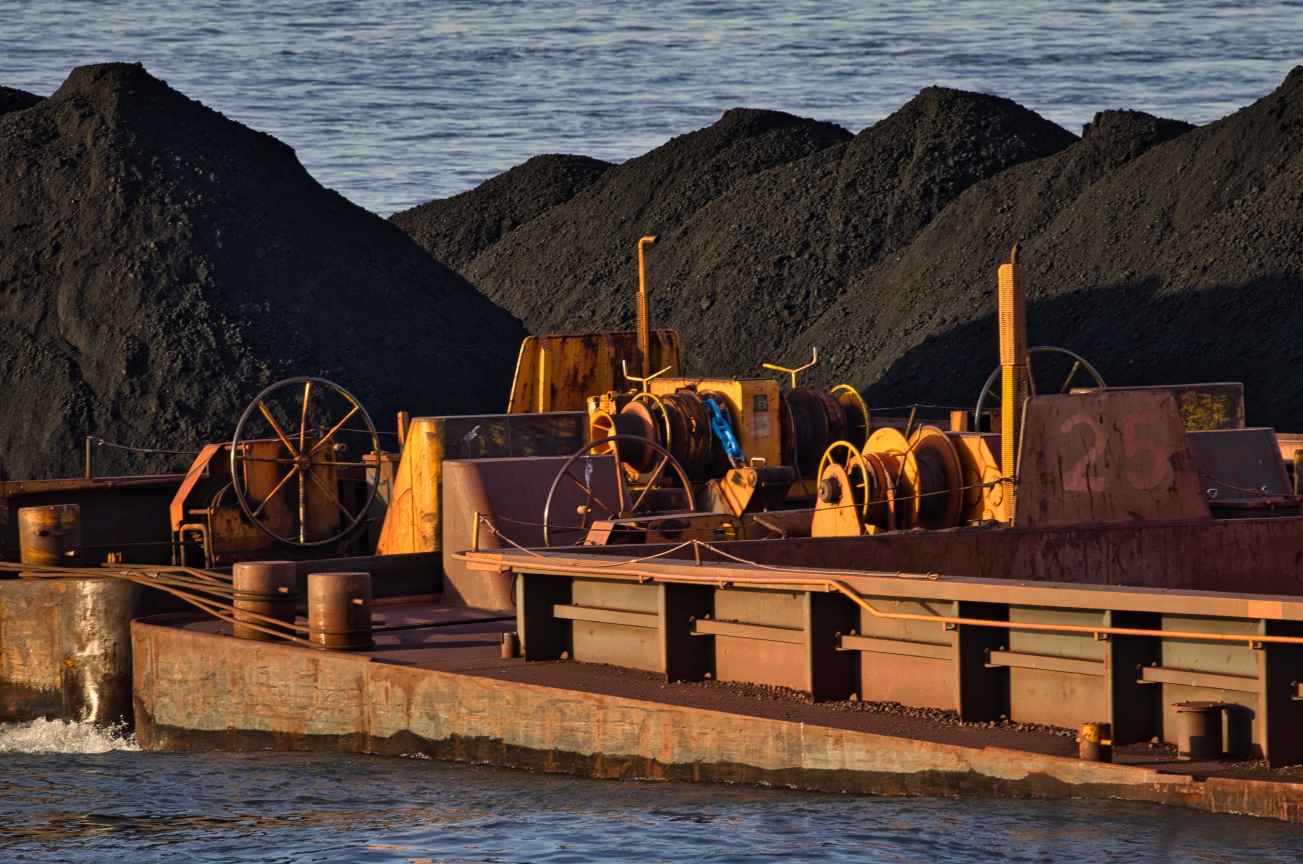 A cargo ship carrying coal on a river, showcasing inland waterway transportation and logistics.